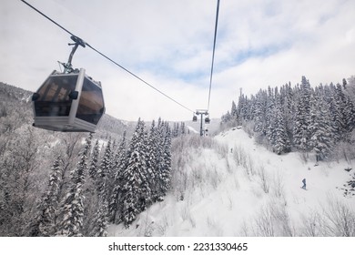 Gondola lift in the ski resort on snow covered slop, winter trees, mountains landscape - Shutterstock ID 2231330465