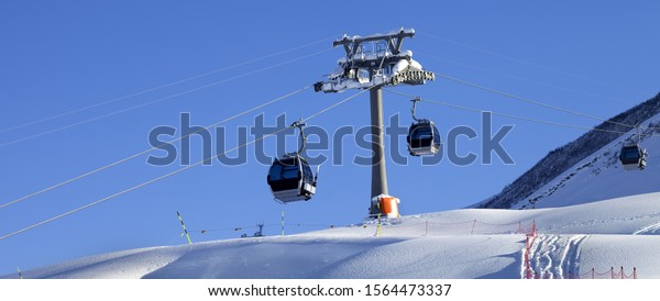 Gondola lift and snowy\
off-piste slope with new-fallen snow on ski resort at sun winter\
evening. Greater Caucasus Mountains, Shahdagh, Azerbaijan.\
Panoramic view.