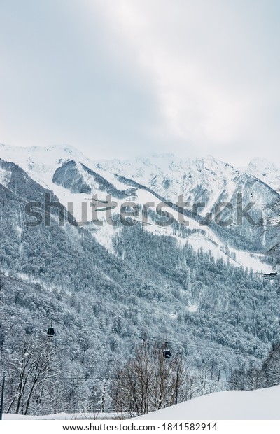 Gondola type 3S - the world\'s longest cable car trunk\
with ring movement. Mining and tourism center Gazprom ski resort.\
Sky road sunny day. Sochi Krasnaya Polyana. View of the\
snow-covered mountains.\
