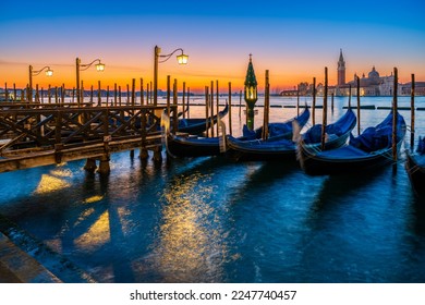 Gondolas floating by the shoreline of San Marco Square at sunrise in front of the Island of San Giorgio Maggiore in Venice, Italy