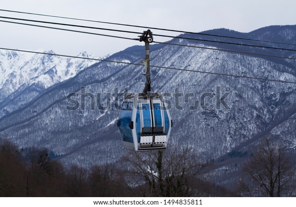 gondola-type cable car\
lift at a ski resort in winter amid mountains and ski slopes with\
skis and\
snowboards