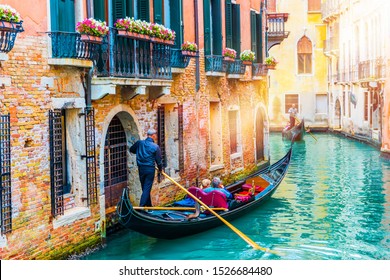 Gondolier carries tourists on gondola in canal of Venice, Italy. Traditional Venice gondola on famous canal. Beautiful Venice view. 