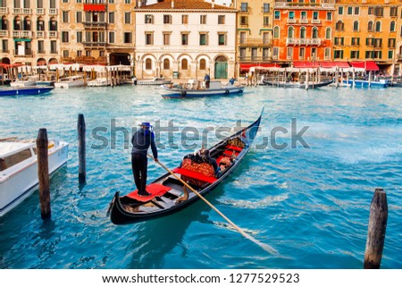 Gondolier carries tourists on gondola Grand Canal of Venice, Italy.