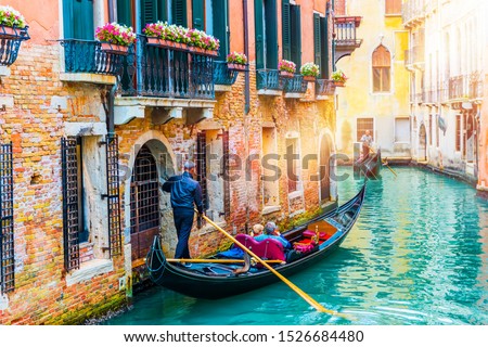 Gondolier carries tourists on gondola in canal of Venice, Italy. Traditional Venice gondola on famous canal. Beautiful Venice view. 
