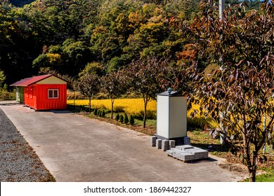 Gongju, South Korea; October 23, 2020: Orange Metal Storage Shed In Countryside Beside Field Of Golden Rice.