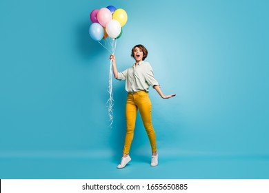 I'm gonna fly. Full size profile photo of funny lady hold many air balloons weekend mood walking down street wear casual green shirt yellow pants footwear isolated blue color background