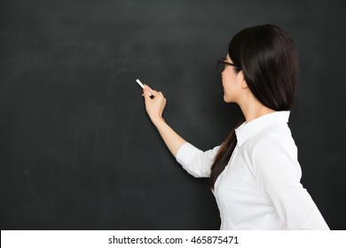 A Good Asian Teacher Writing On Blackboard With Chalk In Classroom