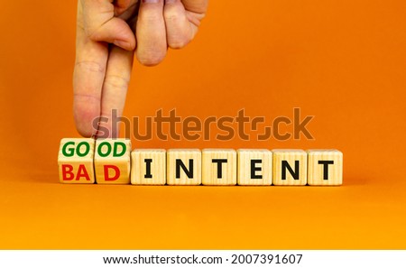 Good or bad intent symbol. Businessman turns wooden cubes and changes words 'bad intent' to 'good intent'. Beautiful orange table, orange background. Business, bad or good intent concept. Copy space.