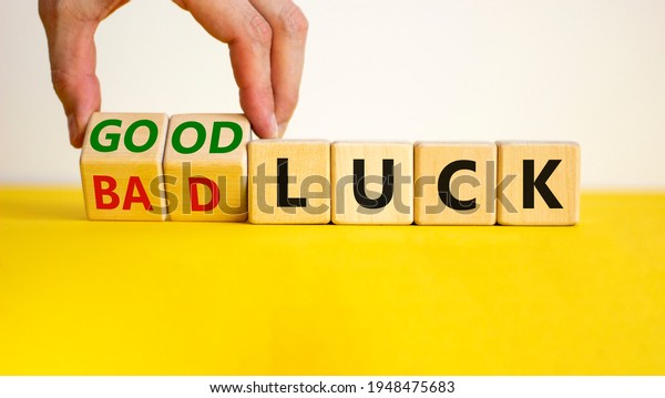 Good or bad luck symbol. Businessman turns\
wooden cubes and changes words \'bad luck\' to \'good luck\'. Beautiful\
yellow table, white background, copy space. Business and good or\
bad luck concept.