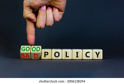 Good or bad policy symbol. Businessman turns wooden cubes and changes words 'bad policy' to 'good policy'. Beautiful grey table, grey background. Business, bad or good policy concept. Copy space.