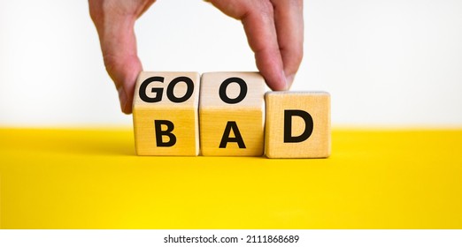Good or bad symbol. Businessman turns wooden cubes and changes the word bad to good. Beautiful yellow table, white background, copy space. Business and bad or good concept. - Shutterstock ID 2111868689
