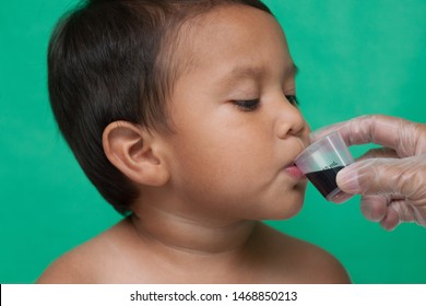 A Good Boy Calmly Taking A Dosage Of Medication For The Common Cold Without Protest From A Nurse.