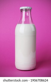 Bon petit déjeuner avec une bouteille de verre pleine de lait frais. Le calcium est bon pour la santé. Photo sur fond rose avec ombre