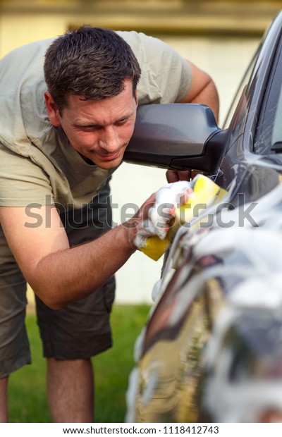 good car wash - Young man washing car with a\
sponge and foam\
