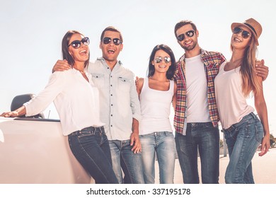 Good day with good friends. Young happy people bonding to each other and smiling while standing near their convertible - Shutterstock ID 337195178