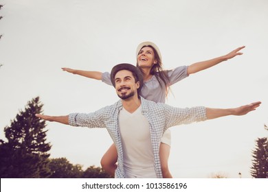 Good day, happiness, friendship, stroll, holiday concept. Cute sweet partner piggybacking his lady, she rides him, they are well dressed, excited, lovely, with spread hands