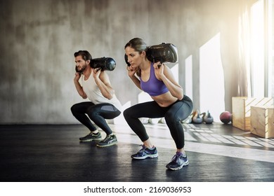Its a good day to lift something heavy. Shot of two young people working out in the gym using weighted bags. - Powered by Shutterstock