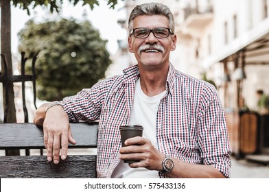 Good day! ?heerful senior man relaxing on park bench and drinking coffee on a summer's day. - Powered by Shutterstock