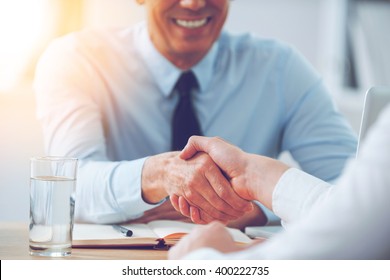 Good deal. Close-up of two business people shaking hands while sitting at the working place - Shutterstock ID 400222735