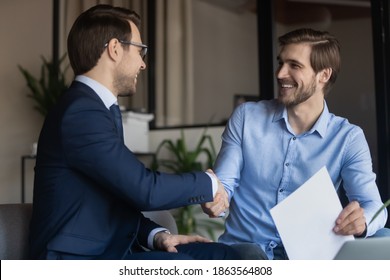 Good deal! Two business partners shaking hands after signing contract, client satisfied of getting loan insuring life handshaking with banker, happy job applicant appreciating hr for receiving place - Shutterstock ID 1863564808