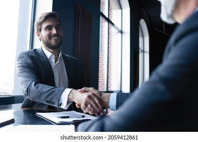 Good Deal. Two Business People Shaking Hands While Sitting At The Working Place.