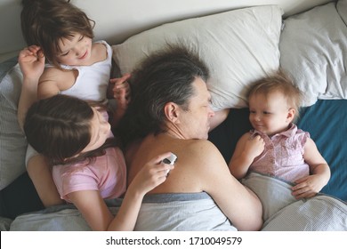 Good Family Morning, The Children Came To Bed To The Sleeping Dad, The Children Play Around The Sleeping Parent. Sunday Morning Or Quarantine Morning