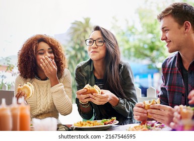 Good food and laughter go hand-in-hand. Cropped shot of three friends eating burgers outdoors. - Powered by Shutterstock