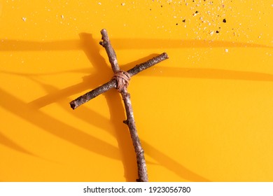 Good Friday, Ash Wednesday, Lent Season and Holy Week concept. Christian cross and ashes on yellow background. Flat lay. Copy space.