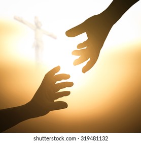 Good Friday concept: Silhouette two hands reaching together over blurred Jesus Christ on cross background.