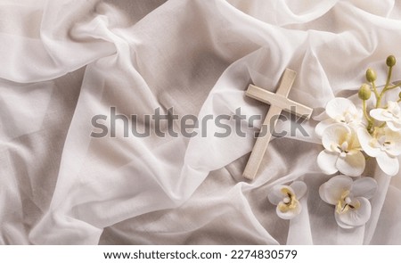 Good Friday and Holy week concept - A religious cross and flower on white fabric background.