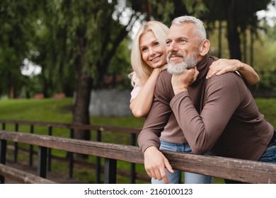 Good future. Happy romantic mature couple spouses hugging embracing together in city park on a date walking outdoors - Shutterstock ID 2160100123