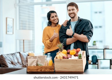 Good health is the way to go. Shot of a happy young couple showing thumbs up after unpacking their healthy groceries at home. - Powered by Shutterstock