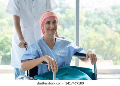 Good Hospital Provide Quality Medical Service. Professional Nurse Take Care A Patient.  Senior Caucasian Woman Cover Head With A Cloth Caused Of Chemotherapy Cancer, Smiling And Sitting On Wheelchair.