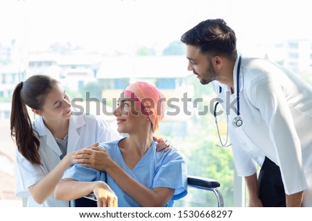 Good hospital provide quality medical service. Professional doctor, nurse take care a patient.  Senior Caucasian woman cover head with a cloth caused of chemotherapy cancer, smiling sitting wheelchair