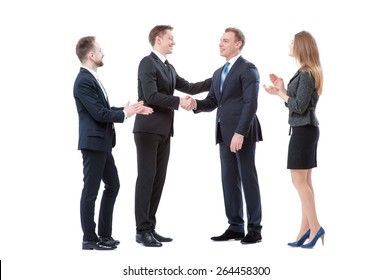 Good Job! Partnership And Congratulations.Two Cheerful Business Men Shaking Hands While Their Colleagues Applauding And Smiling In The Background. Isolated On White.