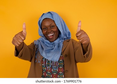 Good Job! Portrait Of A Happy Smiling African American Muslim Young Successful Woman Giving Two Thumbs Up Gesture Standing Indoors. Positive Human Emotion Facial Expression Body Language. Funny Girl