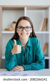 Good job. Successful project. Business webinar. Professional achievement. Satisfied smiling female leader approving with thumb up like gesture at office workplace interior.