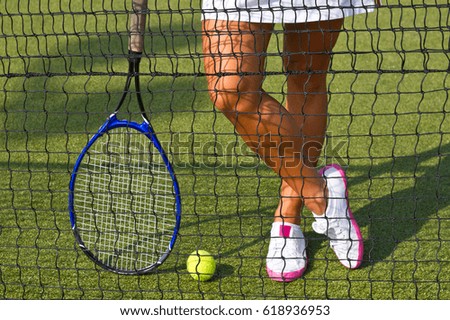Good legs stands with racket on court at sunny summer day