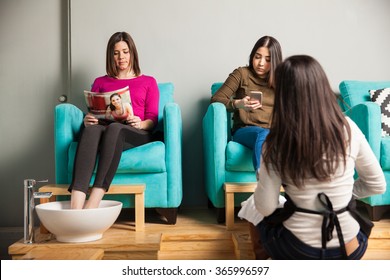 Good Looking Couple Of Women Passing Time And Waiting At A Nail Salon For A Pedicure