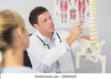 Good looking doctor showing a patient something on skeleton model in bright office - Powered by Shutterstock