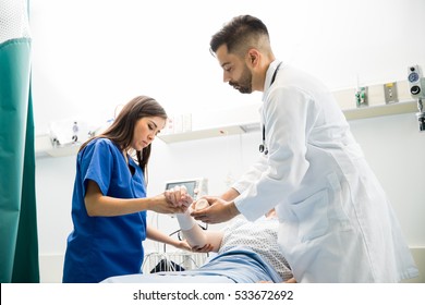 Good Looking Doctors Putting A Bandage On A Patient's Arm After Cleaning A Wound In A Hospital