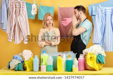 good looking funny guy teasing his girl while doing laundry. close up portrait. man trying make girl happy, entertaining her in the laundry room