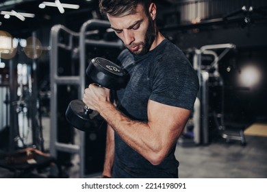 Good Looking Handsome Male Athlete Exercising In Modern Fitness Gym. Dark Muddy Light With Strong Shadows. Indoors Sport Concept.