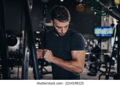 Good Looking Handsome Male Athlete Exercising In Modern Fitness Gym. Dark Muddy Light With Strong Shadows. Indoors Sport Concept.