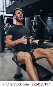 Good Looking Handsome Male Athlete Exercising In Modern Fitness Gym. Dark Muddy Light With Strong Shadows. Indoors Sport Concept.