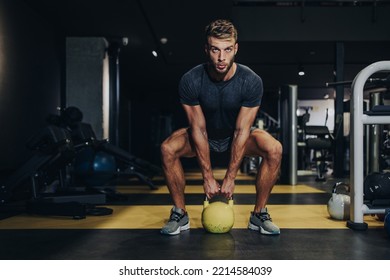 Good Looking Handsome Male Athlete Exercising In Modern Fitness Gym. Dark Muddy Light With Strong Shadows. Indoors Sport Concept.