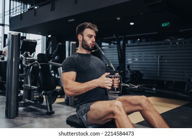 Good Looking Handsome Male Athlete Exercising In Modern Fitness Gym. Dark Muddy Light With Strong Shadows. Indoors Sport Concept.