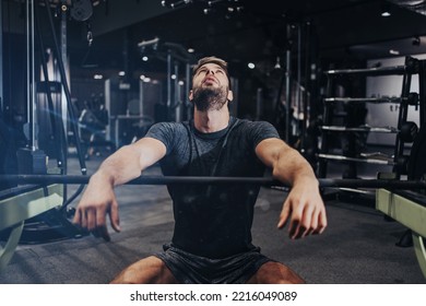 Good Looking Handsome Male Athlete Exercising In Modern Fitness Gym. Dark Muddy Light With Strong Shadows. Indoors Sport Concept.