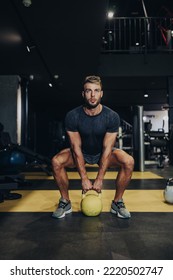 Good Looking Handsome Male Athlete Exercising In Modern Fitness Gym. Dark Muddy Light With Strong Shadows. Indoors Sport Concept.