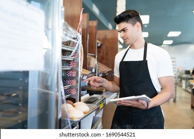 Good looking male worker using a tablet computer to do inventory in a bakery shop - Powered by Shutterstock